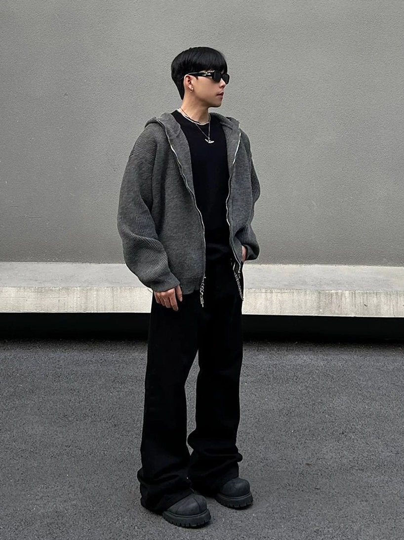 Side profile of a man in a loose charcoal grey zip hoodie highlighting the clean hooded silhouette and relaxed rib-knit texture