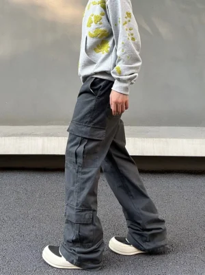Side view of men's washed charcoal gray utility cargo pants with large flap pockets and loose wide flared leg silhouette
