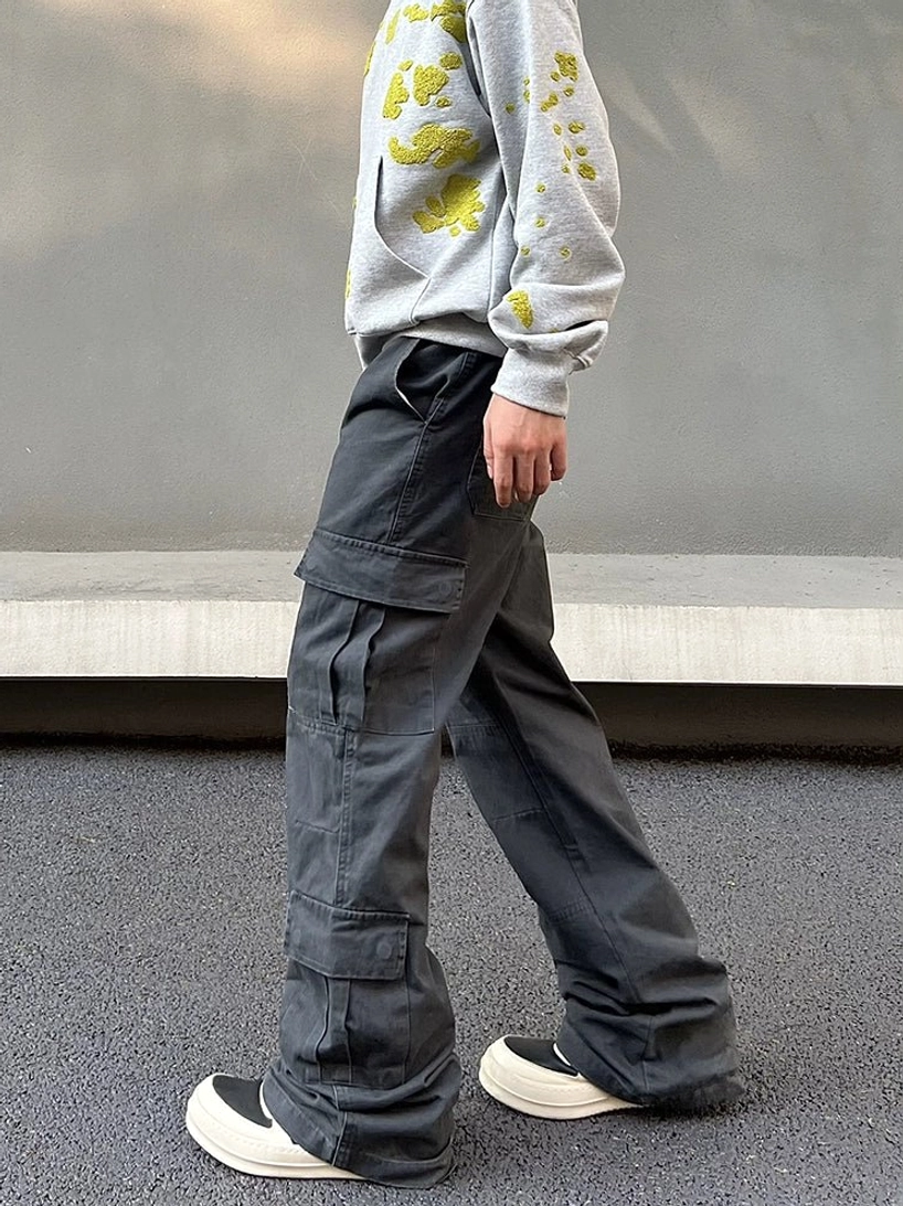 Side view of men's washed charcoal gray utility cargo pants with large flap pockets and loose wide flared leg silhouette
