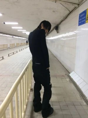 Charcoal black music embroidered slim flare denim jeans worn in a full black underground streetwear outfit from rear low angle