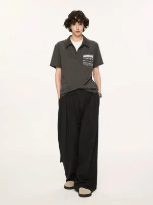 Charcoal relaxed knit polo with Fair Isle inspired chest pocket shown from back three quarter view with black wide leg trousers