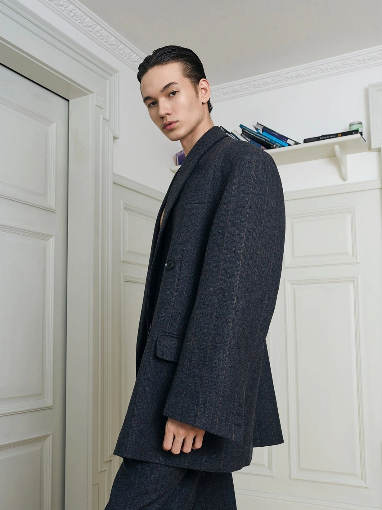 Side view of charcoal textured oversized double-breasted blazer with broad shoulders and relaxed sleeves