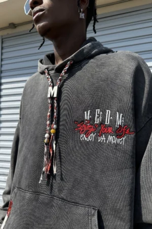 Close-up side view of charcoal washed embroidered oversized hoodie showing faded fabric texture braided drawcord and metal charm