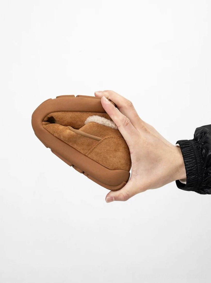 Chestnut brown foldable shearling slip-on clogs held in hand, showing the soft fleece lining, suede-style upper, and flexible rubber outsole