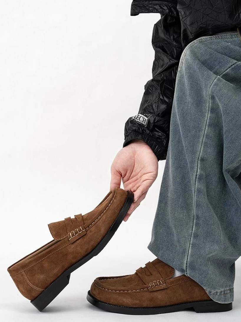 Side profile of a chestnut brown suede penny loafer showing the low heel, textured upper, contrast stitching, and lightweight rubber outsole
