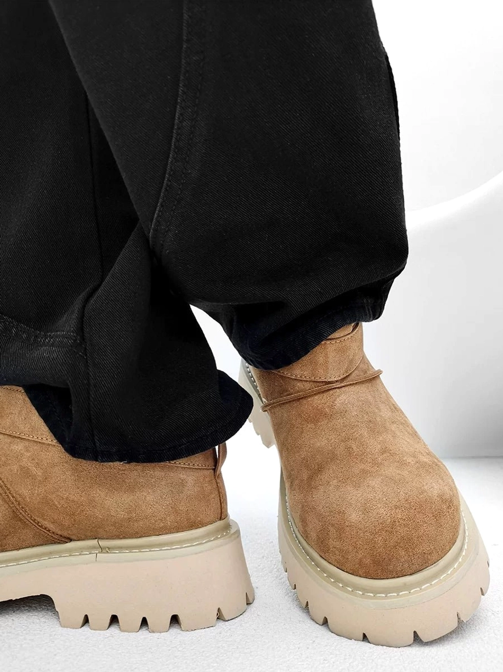 Chestnut brown suede platform ankle boots worn with black pants, featuring fleece lining and a thick beige lug outsole