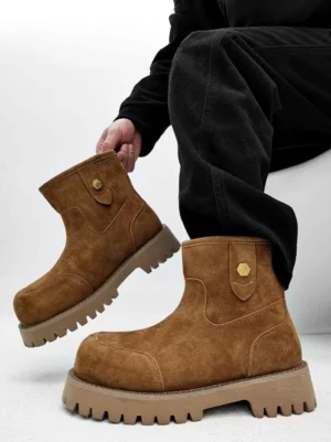 Chestnut brown suede work boots with chunky lug soles and hexagonal metal collar detail displayed with black trousers
