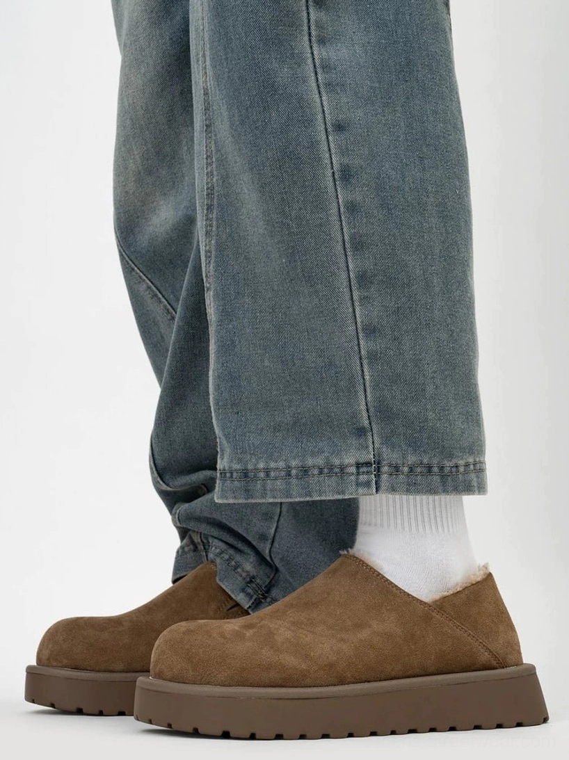 Chestnut shearling-lined platform slip clogs worn with jeans and white socks, showing the low-cut slip-on shape, rounded toe, and elevated rubber platform sole