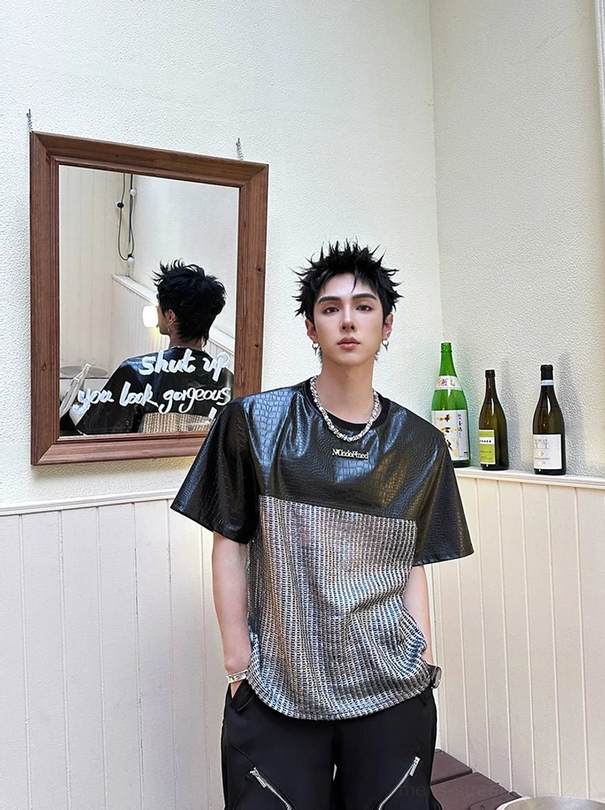 Front view of the relaxed chrome grid patchwork techwear T-shirt with black faux-leather upper panels, silver woven torso, and layered necklace styling