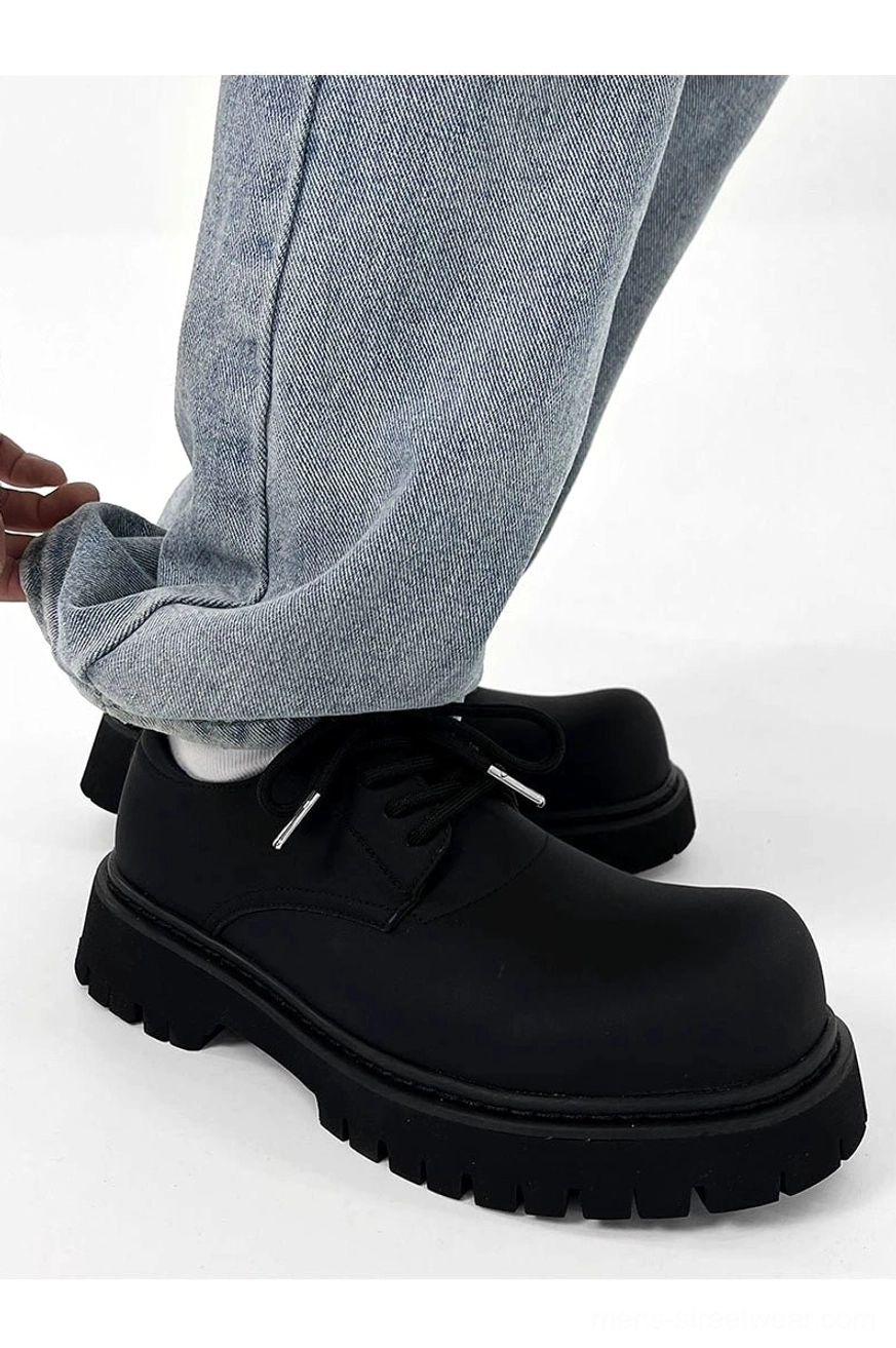 Chunky black matte platform derby shoe worn with light blue jeans showing the heel counter and textured lug outsole