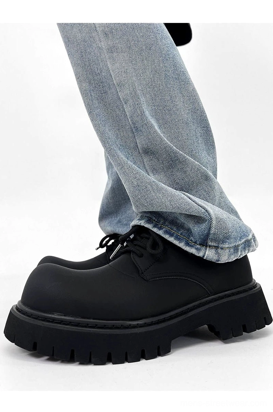 Side profile of a chunky black platform derby shoe worn with cuffed light blue jeans and a thick lug sole