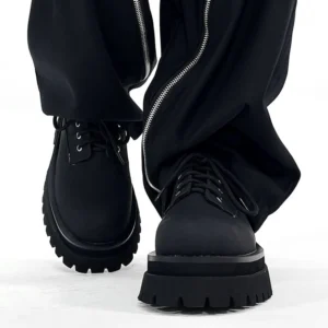 Black platform derby shoes worn with black streetwear trousers showing lace-up front and chunky rubber sole