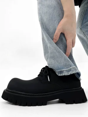 Chunky black matte platform derby shoe worn with light blue jeans showing the rounded toe lace-up upper and thick lug sole