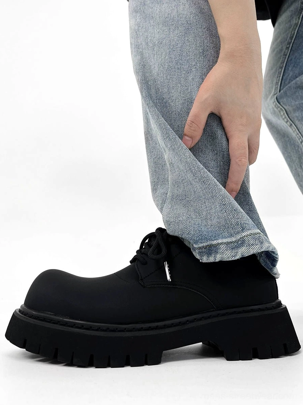 Chunky black matte platform derby shoe worn with light blue jeans showing the rounded toe lace-up upper and thick lug sole