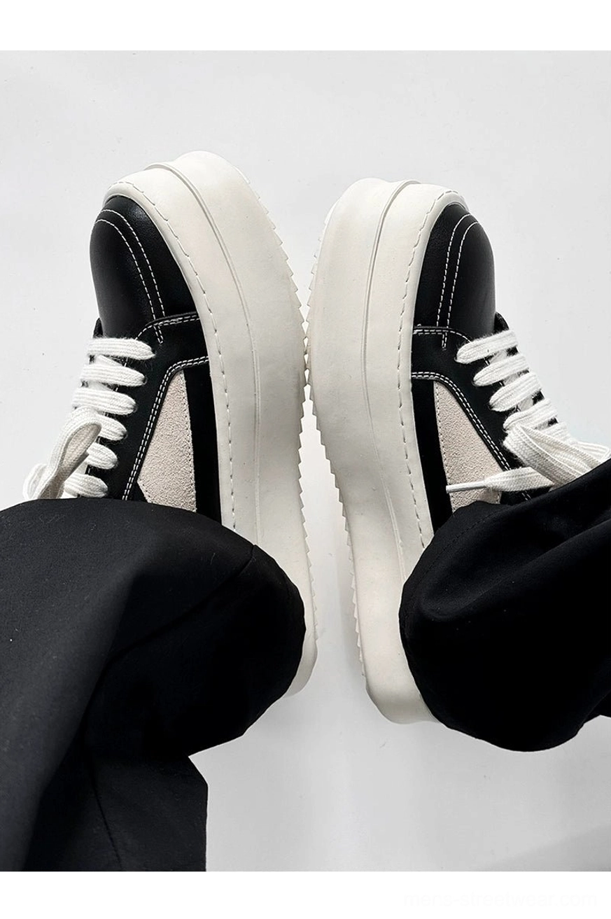 Rear view of chunky black platform sneakers with beige side accents and white lace details