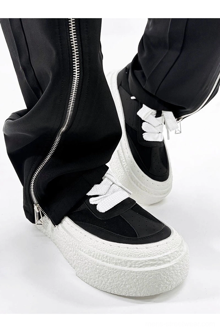 Chunky black and white platform sneakers shown from a low three-quarter angle with textured thick soles