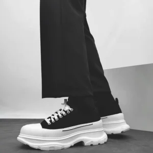 Black and white chunky platform canvas sneakers worn with tailored black trousers in a low side streetwear view