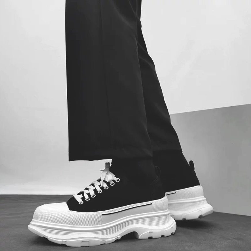 Black and white chunky platform canvas sneakers worn with tailored black trousers in a low side streetwear view