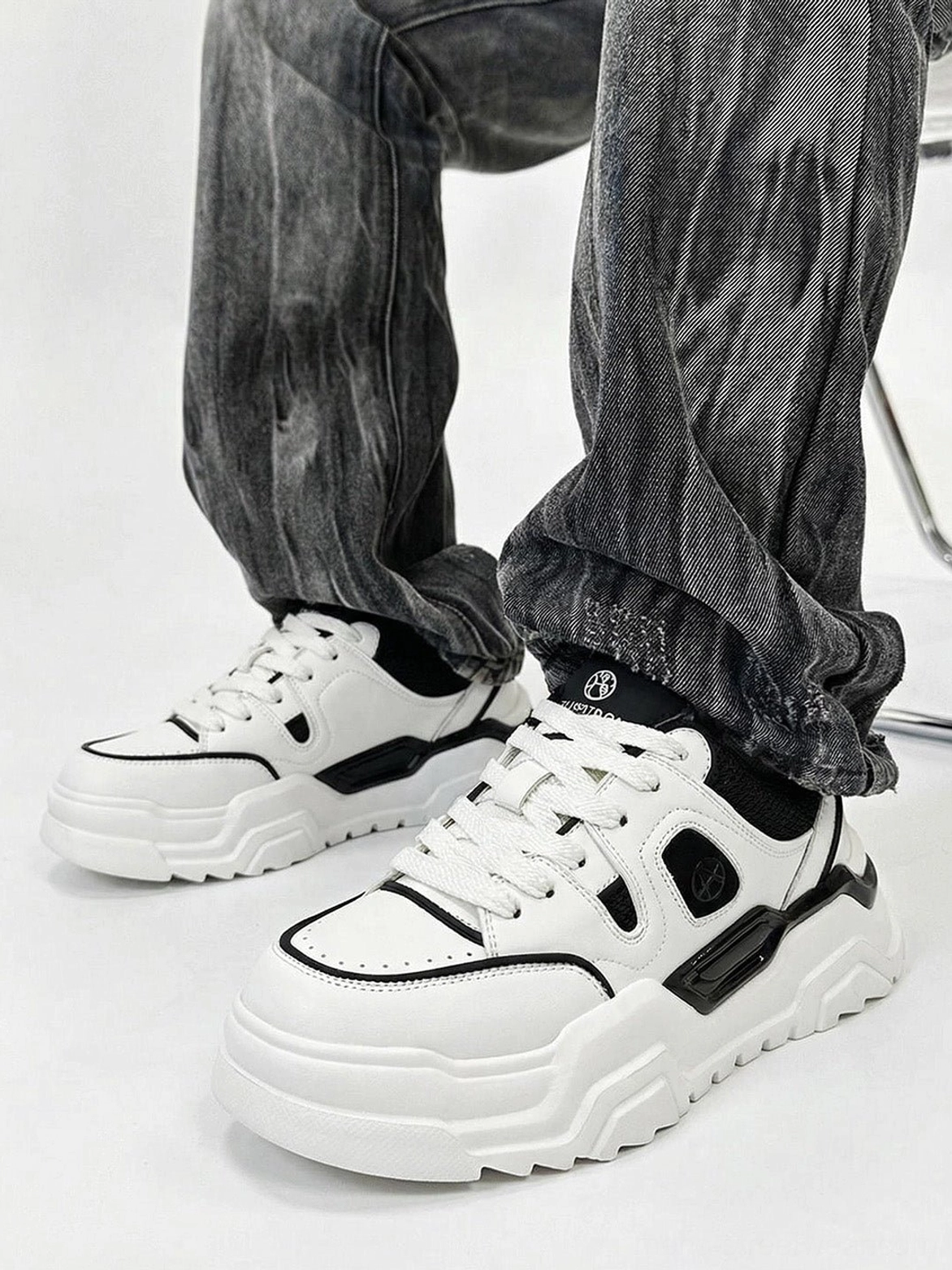 Model wearing black and white platform sneakers styled with vintage gray washed jeans worn on-foot ground level perspective showcase
