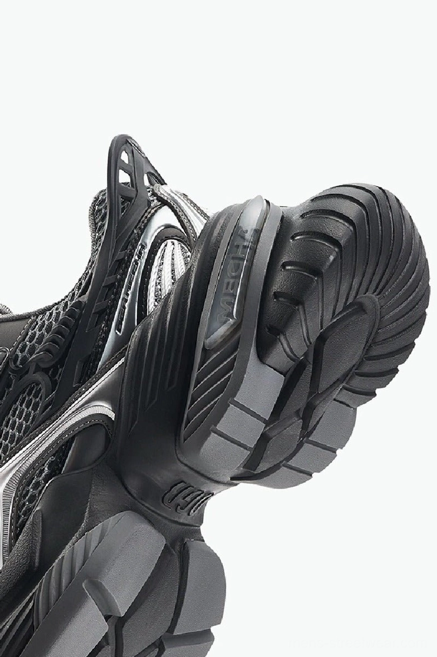 Close-up underside view of chunky platform sneaker with deep rugged tread pattern and sculpted black rubber outsole
