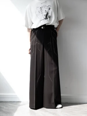 Back three-quarter view of black wide leg streetwear trousers with geometric circuit-inspired topstitching, tailored fabric, leather belt, and metal buckle