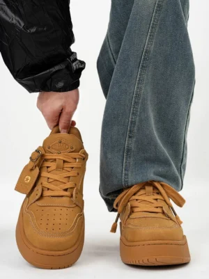 Wheat suede-style platform skate sneakers shown from the front with one shoe held and a pair worn with baggy blue jeans and a black streetwear windbreaker