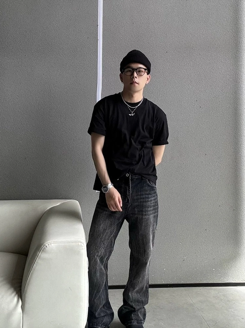 Front view of a black minimalist crew neck T-shirt styled with washed wide-leg jeans and layered silver necklaces