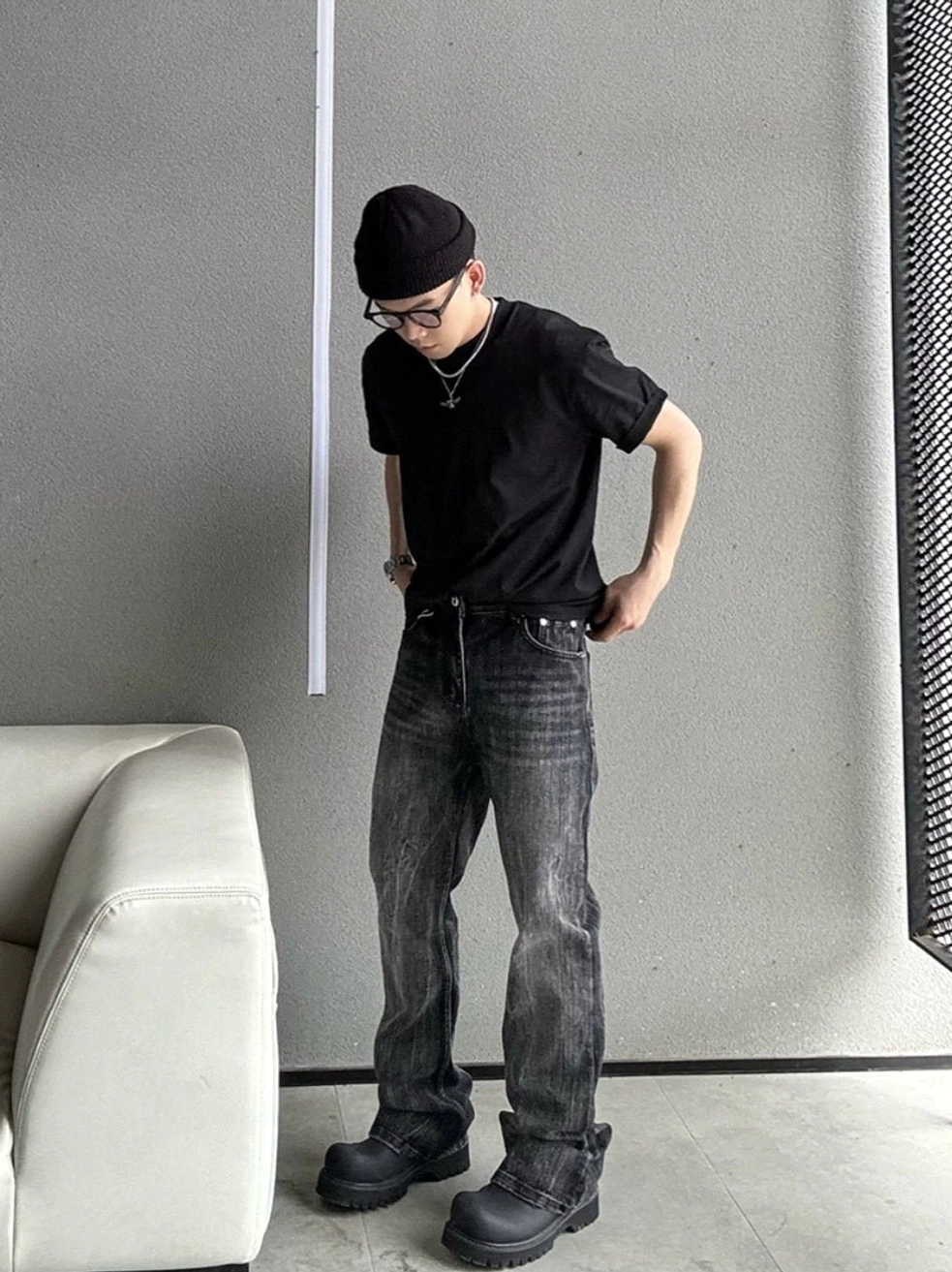 Side three-quarter view of a black relaxed fit basic T-shirt styled with washed straight-leg jeans for urban streetwear