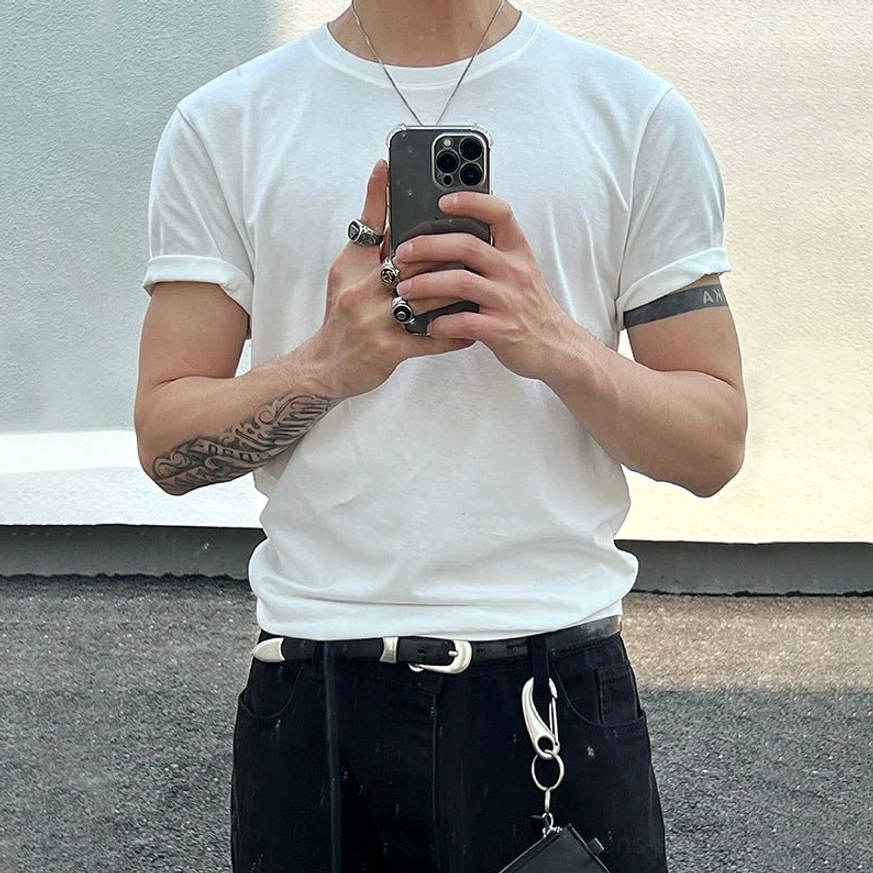 White minimalist crew neck T-shirt with rolled sleeves styled with black denim, silver necklaces, and rings