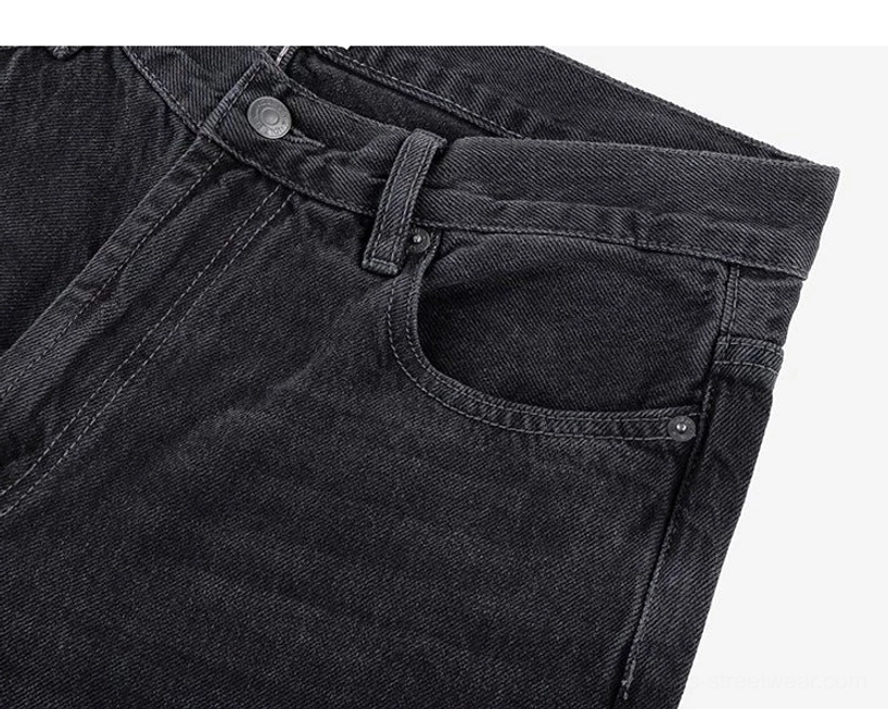 Side waist close-up of washed black wide-leg jeans featuring reinforced pocket stitching, metal rivets, and cotton denim texture