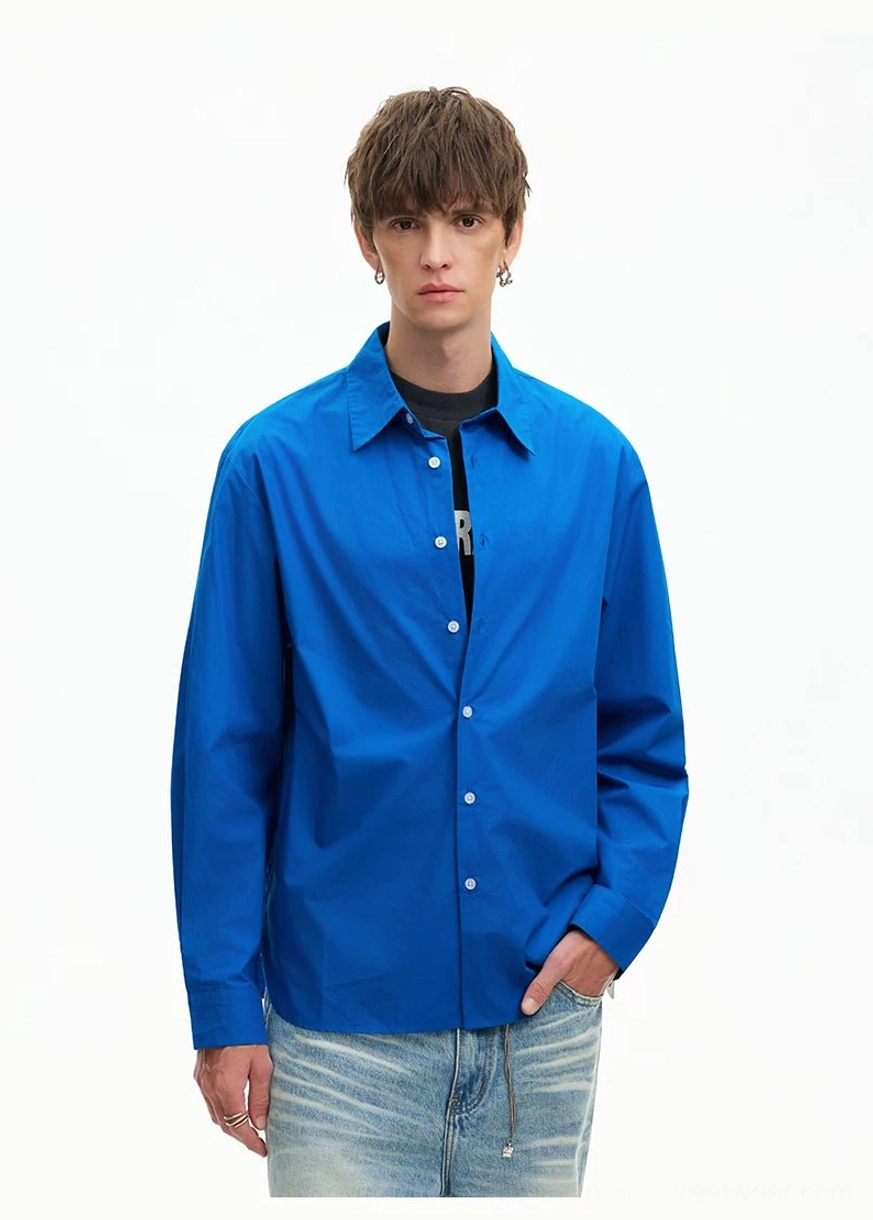 Close front view of a Royal Blue oversized poplin shirt featuring a pointed collar and smooth solid-color finish