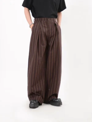 Coffee brown pinstripe wide-leg trousers shown from the front with high waist deep pleats and relaxed streetwear silhouette