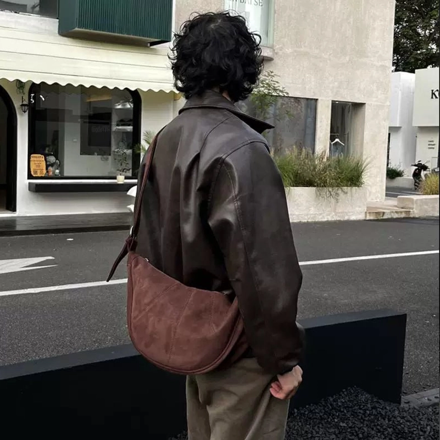 Coffee brown vintage crescent crossbody sling bag worn with brown leather jacket on a sunny cafe street