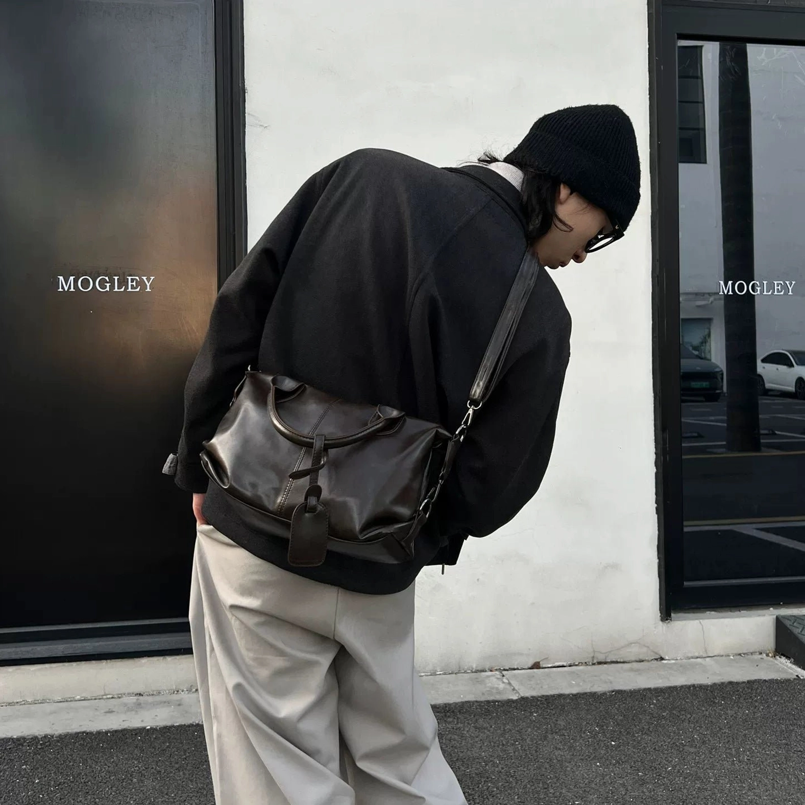 Coffee brown vintage faux leather bowling bag worn crossbody with black streetwear and khaki trousers