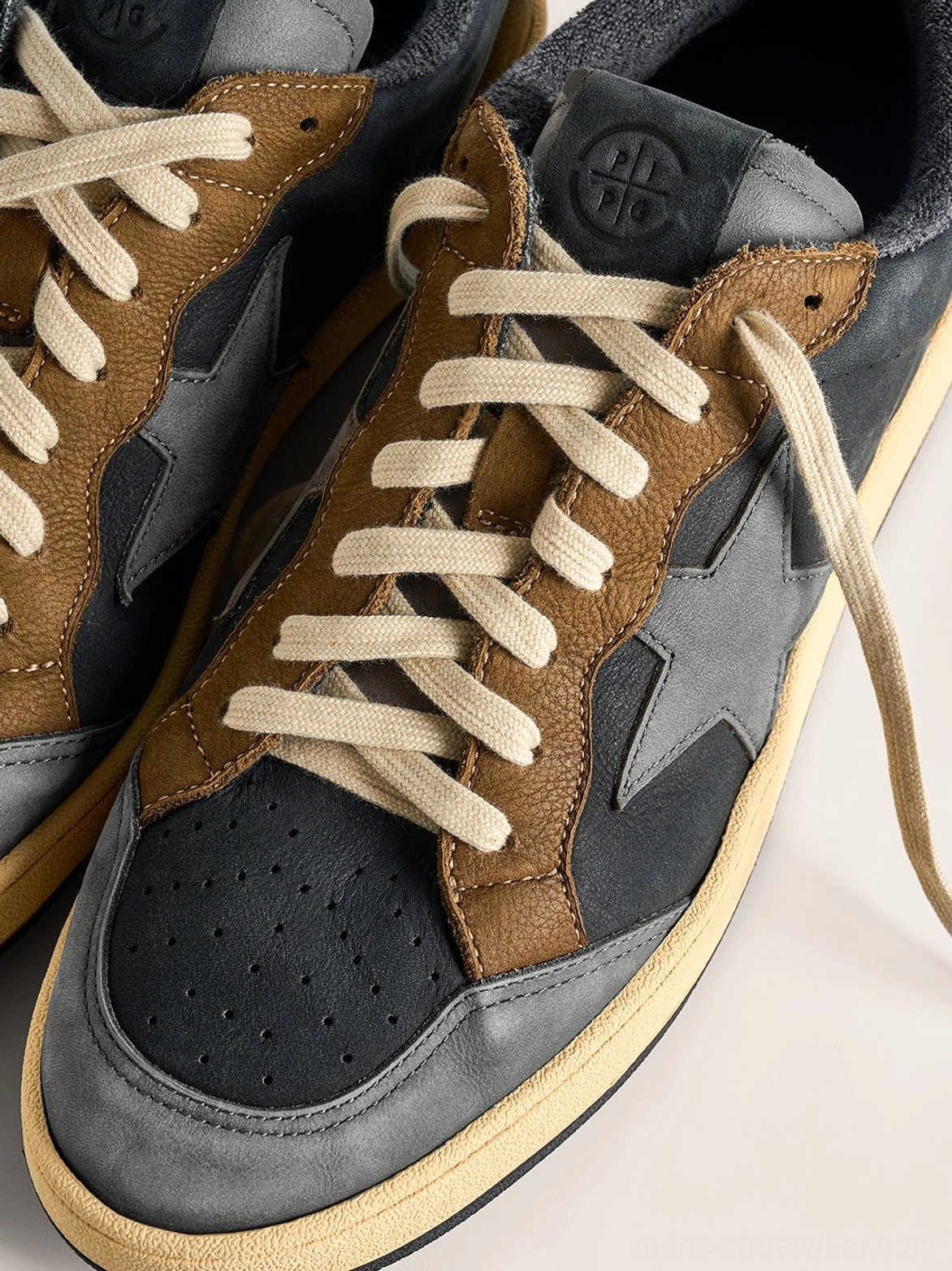 Close-up overhead view of coffee and gray retro star panel sneakers showing perforated toe boxes, flat laces, leather panels, and tongue details
