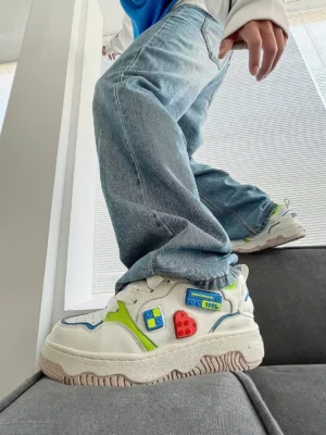 Rear three-quarter on-foot view of colorful building brick chunky platform skate sneakers styled with baggy light blue jeans