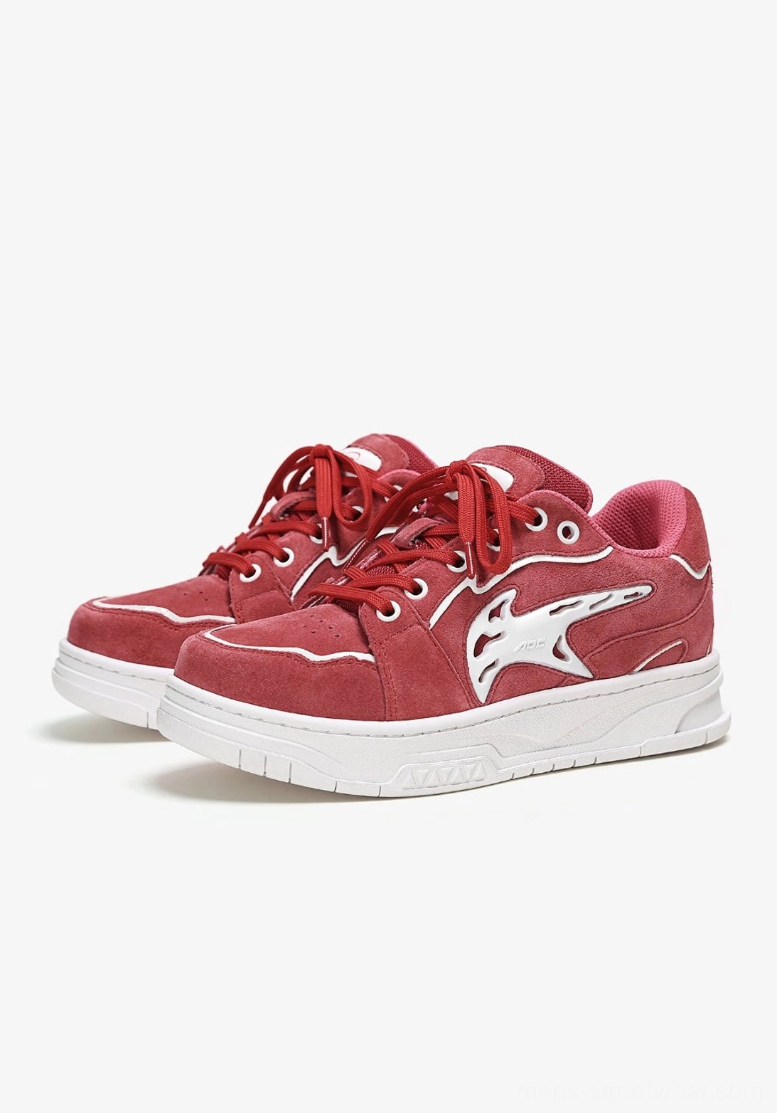 Pair of red low-top skate sneakers shown from the front with white outlined stitching, graphic side details, and thick white outsoles