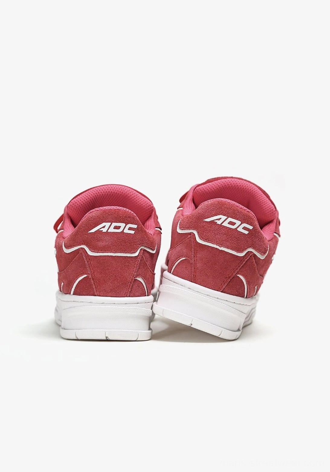 Rear view of paired red low-top skate sneakers showing structured heel counters, textured uppers, and thick white rubber soles