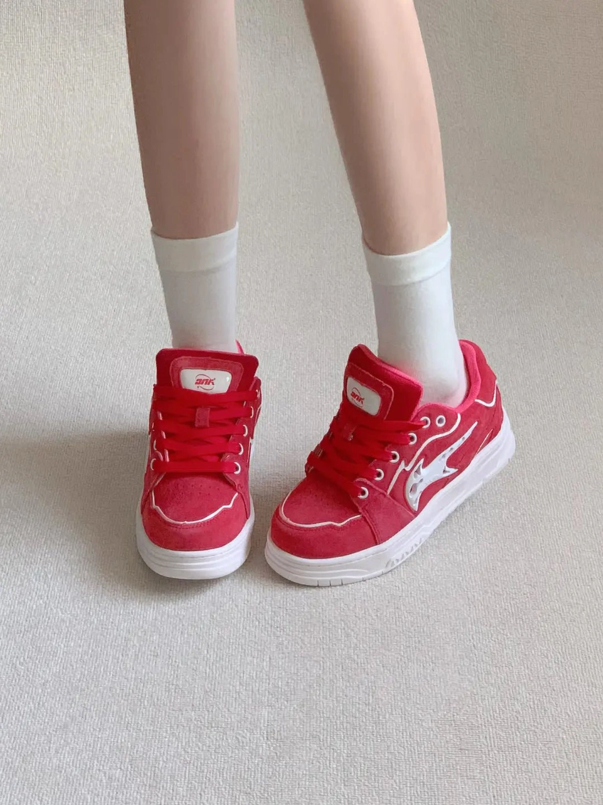 Red color-pop skate sneakers viewed from above on a casual outfit, featuring white side detailing, tongue labels, and contrast rubber soles