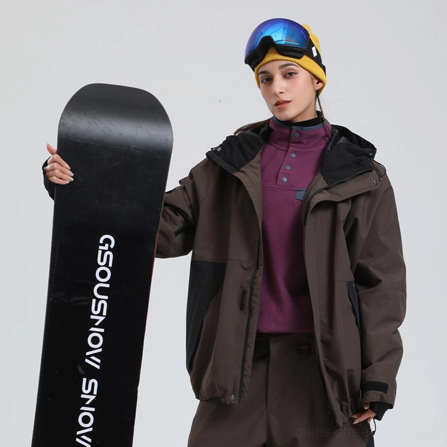 Brown and black colorblock snowboard shell jacket with loose fit, hood and black sleeve panels styled for snowboarding