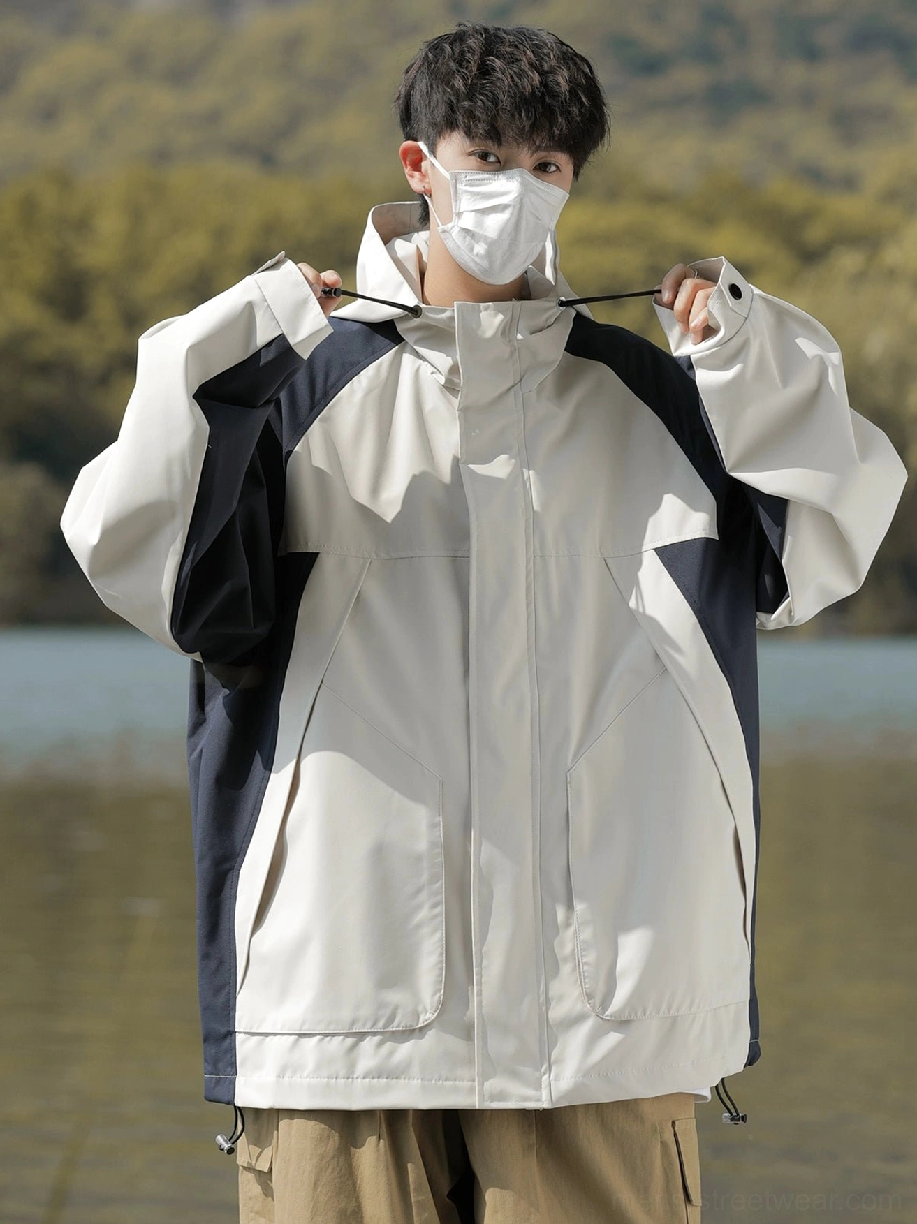 Front view of off-white and dark navy colorblock hooded windbreaker jacket with zipper snap buttons and utility pockets