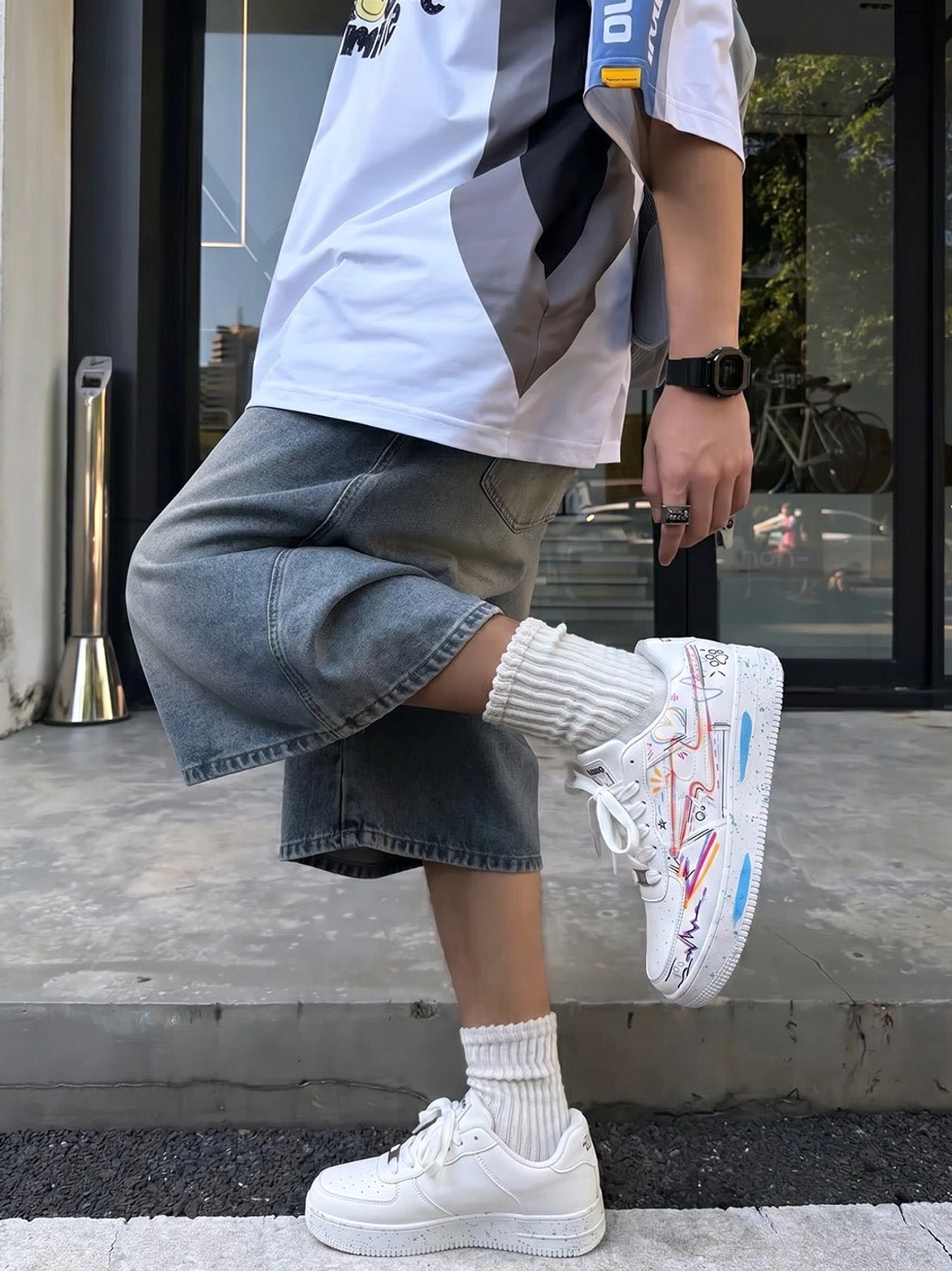 Colorful graffiti lightning court sneaker shown in a streetwear outfit with a colorblock tee and wide denim bottoms