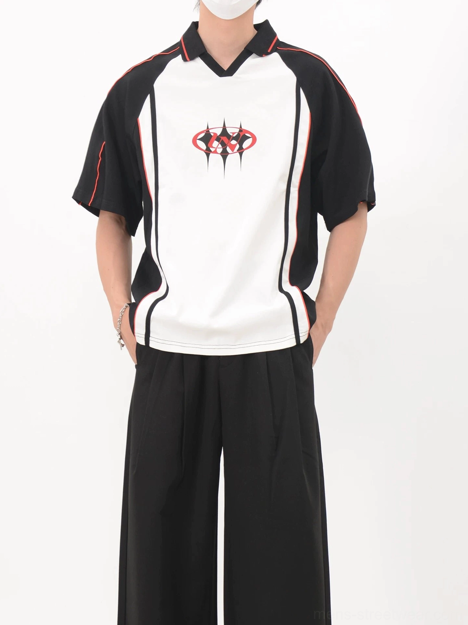 Front view of a contrast black and white soccer jersey shirt with red piping, raglan sleeves, chest crest, and relaxed Korean streetwear styling