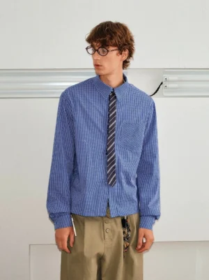 Male model wearing a blue checked contrast collar shirt and striped tie set with khaki trousers in a minimalist studio