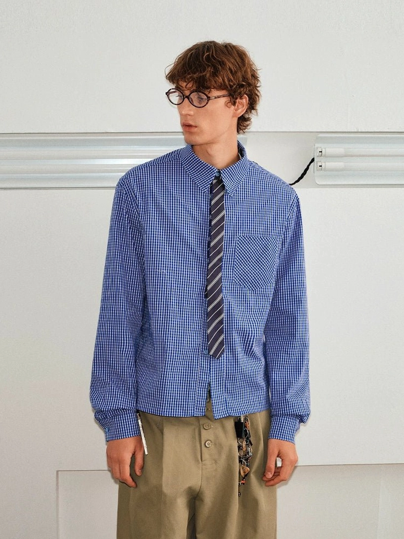 Male model wearing a blue checked contrast collar shirt and striped tie set with khaki trousers in a minimalist studio