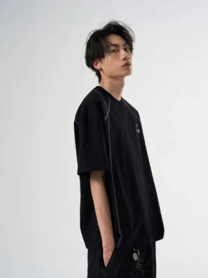 Black relaxed fit graphic T-shirt with contrast seam stitching and small chest detail shown on a male model in a studio