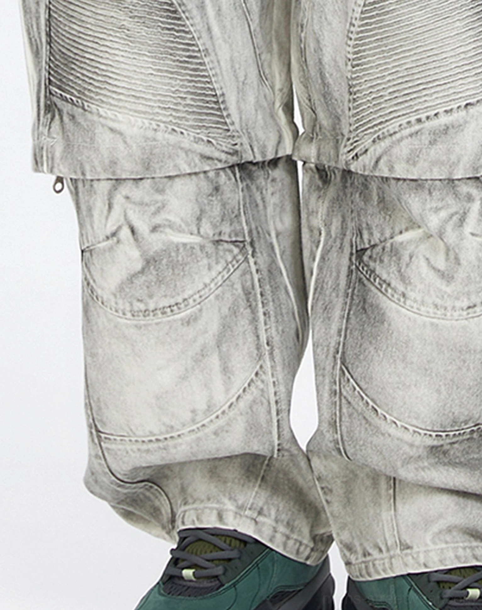 Close up of faded convertible cargo pants showing ribbed knee stitching, detachable leg zipper, worn texture, and outdoor sneaker detail