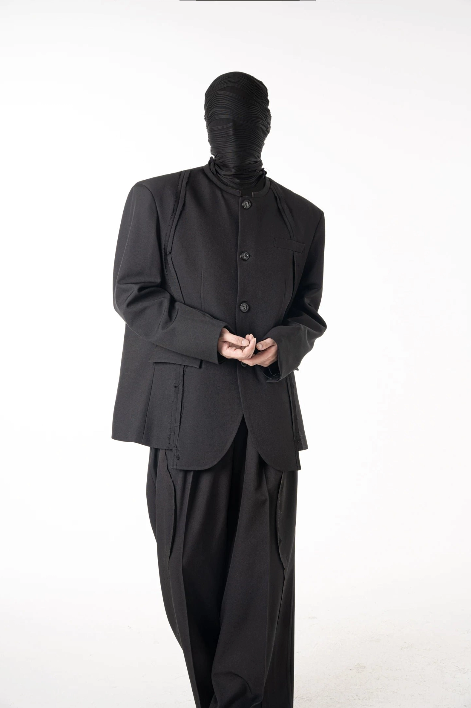 Full body front view of coordinated all-black suit featuring stand collar blazer subtle seams and wide-leg tailored pants