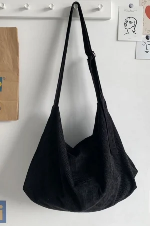Black corduroy slouchy crossbody bag with adjustable strap, metal buckle, and relaxed oversized streetwear silhouette