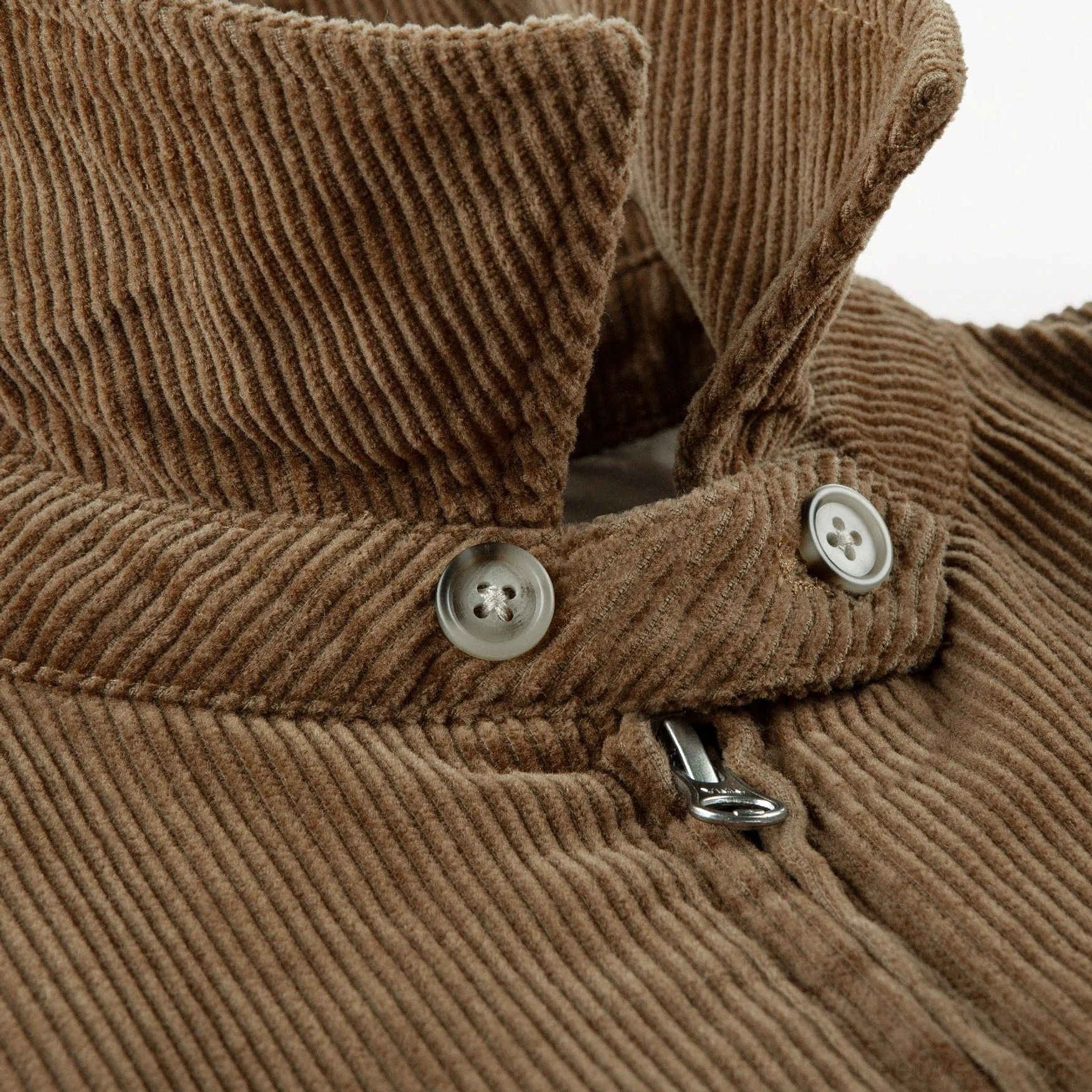 Close-up of wide-wale corduroy Harrington jacket collar with adjustment buttons metal zipper pull and textured cotton fabric